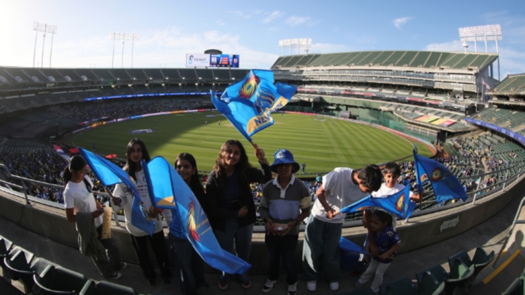 MI New York fans waving team flags at a Major League Cricket (MLC) 2025 match in Oakland Stadium, showing enthusiastic support for their team.